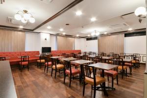Hotel Castle Inn Yokkaichi في يوكايتشي: قاعة اجتماعات مع طاولات وكراسي وشاشة