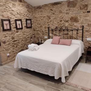 ein Schlafzimmer mit einem großen Bett in einer Steinmauer in der Unterkunft Casal da Ponte nas Rías Baixas in Boiro