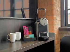 a desk with a clock and cups on it at Bloc Hotel Birmingham in Birmingham