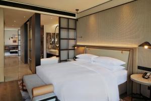 a bedroom with a large white bed and a living room at Sheraton Taizhou in Taizhou