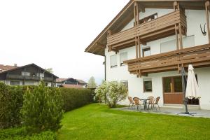 ein Haus mit einem Garten mit Stühlen und einem Sonnenschirm in der Unterkunft Ferienwohnung Heigel in Oberstdorf