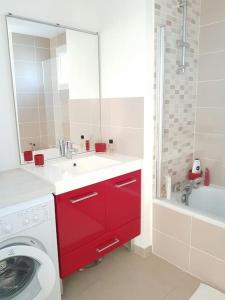 La salle de bains est pourvue d'un lavabo rouge et d'un lave-linge. dans l'établissement AppartCosy 50 m2 (avec garage), à Bordeaux