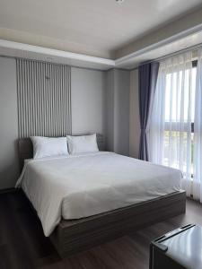 a bedroom with a large white bed with a window at Thiên Ân Hotel in Thôn Dương Phẩm