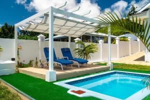 a pool with chairs and a pergola next to a house at Villa Jasmin in Bel Ombre