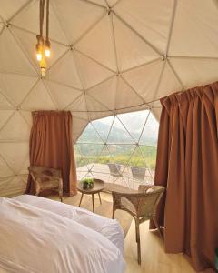 a bedroom with a tent with a bed and a table at A'moss Farmstay in Cameron Highlands