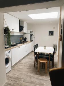 a kitchen with white cabinets and a table and chairs at Maison cosy avec 3 chambres et 3 salles de bains in Amiens