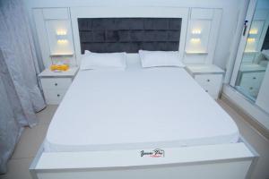 a white bed in a room with two night stands at CAB LFS SIPRES MOURTADA 3e ETAGE in Dakar