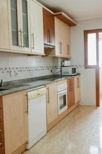 una cocina con electrodomésticos blancos y armarios de madera en Apartamentos Turisticos Playa Principe, en La Manga del Mar Menor