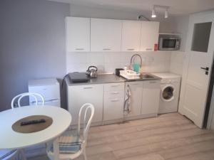 a kitchen with white cabinets and a table and a washing machine at Apartamenty Przy Rynku in Żnin