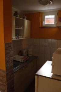 Hócza Apartman في بوغاتش: مطبخ بجدران برتقالية وقمة منضدة