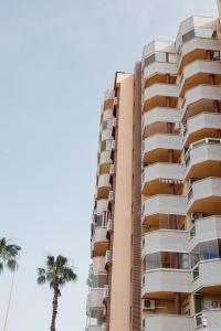 ラ・マンガ・デル・マール・メノールにあるApartamentos Turisticos Playa Principeのヤシの木が目の前にそびえる高い建物