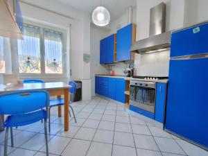 a kitchen with blue cabinets and a table and blue chairs at Brezza d'Estate - L'Opera Group in La Spezia