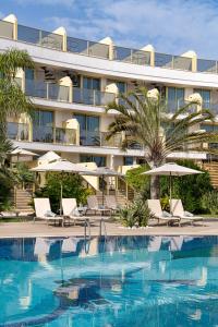 a hotel with a swimming pool with chairs and umbrellas at Sir Anthony in Playa de las Americas