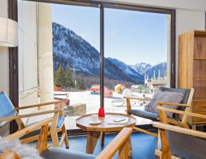 イゾラ 2000にあるSOWELL HOTELS Le Pas du Loupのバルコニー(椅子、テーブル付)、大きな窓が備わります。