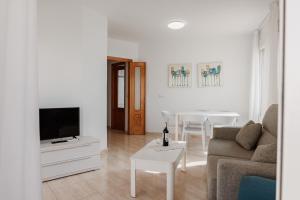 sala de estar con sofá, TV y mesa en Apartamentos Vistamar, en La Manga del Mar Menor