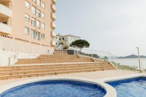 una piscina frente a un edificio con escaleras en Apartamentos Vistamar, en La Manga del Mar Menor