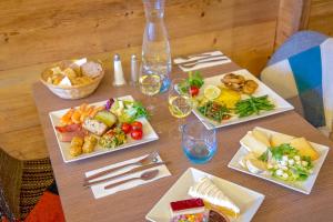 a table with three plates of food and glasses of wine at SOWELL HOTELS Le Pas du Loup in Isola 2000