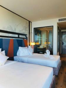 two beds in a hotel room with a mirror at Mandala Cham Bay Mũi Né view biển in Ấp Thiẹn Ái