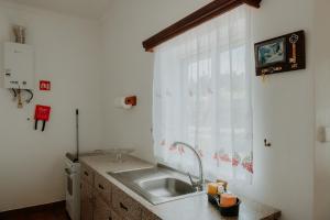 a kitchen with a sink and a window at Casa Sousa Ribeiro in Praia da Vitória