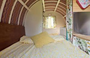 um quarto com uma cama com uma almofada amarela em Clissmann Horse Caravans Glamping em Rathdrum