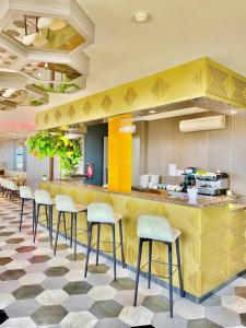 a restaurant with a yellow counter with stools at Arthama Tanah Abang Jakarta in Jakarta