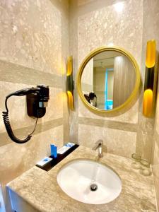 a bathroom with a sink with a mirror and a phone at Arthama Tanah Abang Jakarta in Jakarta