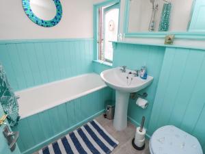 a bathroom with a sink and a tub and a toilet at Riverdance Cottage in Lyme Regis +30 photos