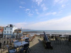 a cannon on a patio near the ocean with tables and chairs at Riverdance Cottage in Lyme Regis