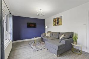 Beautiful 3 bedroom Home in Cambridgeshire في Easton on the Hill: غرفة معيشة مع أريكة رمادية والجدار الأزرق