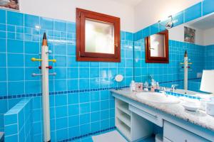 a blue tiled bathroom with a sink and mirror at Villa Briziola in San Teodoro