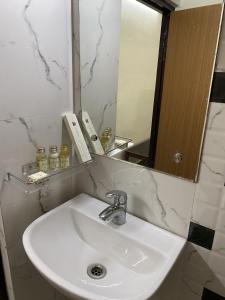 La salle de bains est pourvue d'un lavabo blanc et d'un miroir. dans l'établissement Hotel Mayur, à Purulia