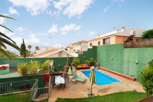 a backyard with a swimming pool and a green wall at Villa Palmeras, un remanso de paz in Candelaria