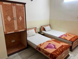 普鲁利耶Hotel Mayur的一张位于小房间内的两张床,上面有紫色帽子