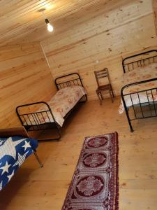 een kamer met 2 bedden en een tapijt in een hut bij guest house "BETQIL" adishi in Adishi