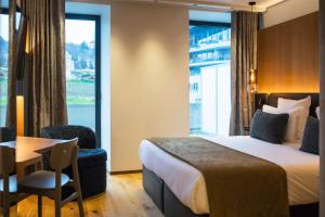 Habitación de hotel con cama, mesa y ventana en Le Pélican, en Annecy