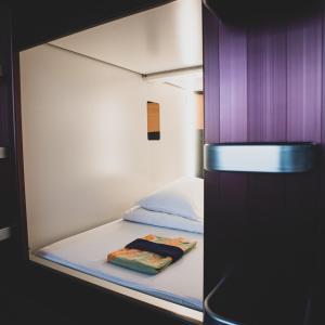 małe łóżko w małym pokoju z fioletowymi ścianami w obiekcie Nadeshiko Hotel Shibuya (Female Only) w Tokio