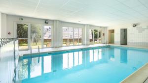 a large swimming pool with blue water in a building at Les Grizzlis - 22 - Appart montagne PMR - 4 pers in Saint-Sorlin-dʼArves