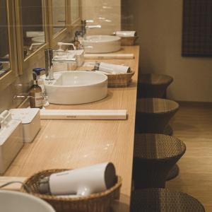 una fila de lavabos y espejos en el baño en Nadeshiko Hotel Shibuya (Female Only) en Tokio