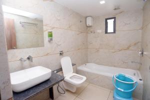 een badkamer met een wastafel, een toilet en een bad bij HOTEL LEE GOLD in Anand