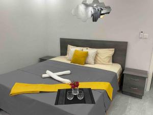 - une chambre avec un lit avec une couverture jaune et deux verres dans l'établissement Maison de ville à Flic-en-Flac, à Flic-en-Flac