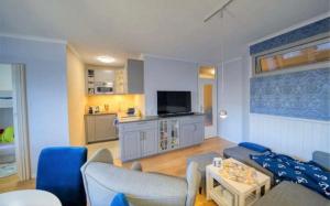 a living room with blue furniture and a kitchen at Oase an der Ostsee mit 2 Schlafzimmern in Heiligenhafen