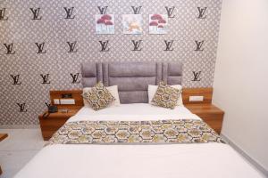 阿南德HOTEL LEE GOLD的卧室里有一张床，墙上写着“V”字 更多14张照片