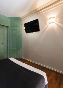 a bedroom with a bed and a flat screen tv on the wall at Hôtel du Dauphin in Lyon