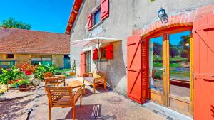 une terrasse avec des chaises, une table et un parasol dans l'établissement Calme et chaleureux gîte de campagne., à Voiteur