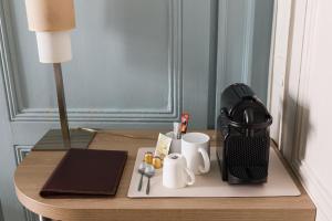 a table with a laptop and a coffee maker on it at Hôtel du Dauphin in Lyon
