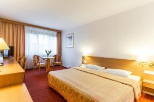 ein Hotelzimmer mit einem großen Bett und einem Tisch in der Unterkunft Hotel Solny in Kołobrzeg