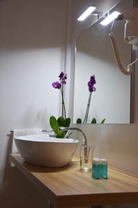 La salle de bains est pourvue d'un lavabo et de fleurs sur un comptoir. dans l'établissement Hotel Imperiale & Spa, à Fiuggi