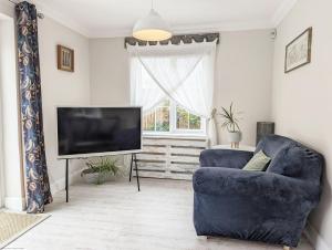 a living room with a blue couch and a television at Sweetpea Cottage in Hambrook