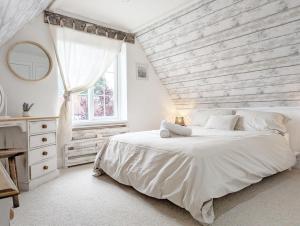 a white bedroom with a large bed and a window at Sweetpea Cottage in Hambrook