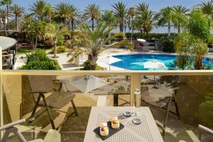 a balcony with a view of a pool and palm trees at Sir Anthony in Playa de las Americas